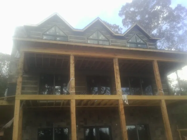 Dormers and porch framing on a large log home under construction — Roof Coating work by our crew in Carroll