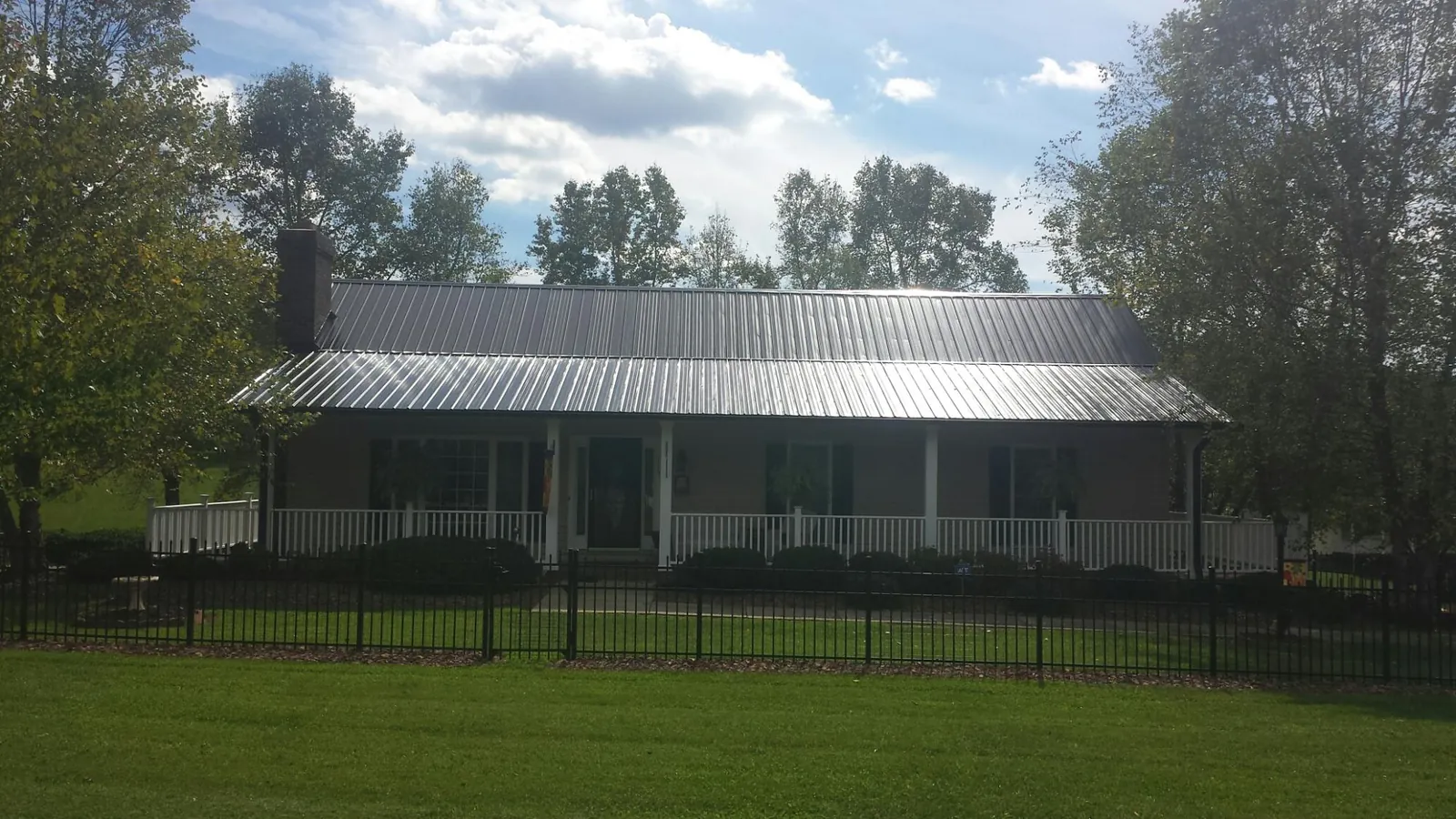 Gray metal roof on a brick ranch with a full width front porch — Gutter Guard Installation work by our crew in Carroll