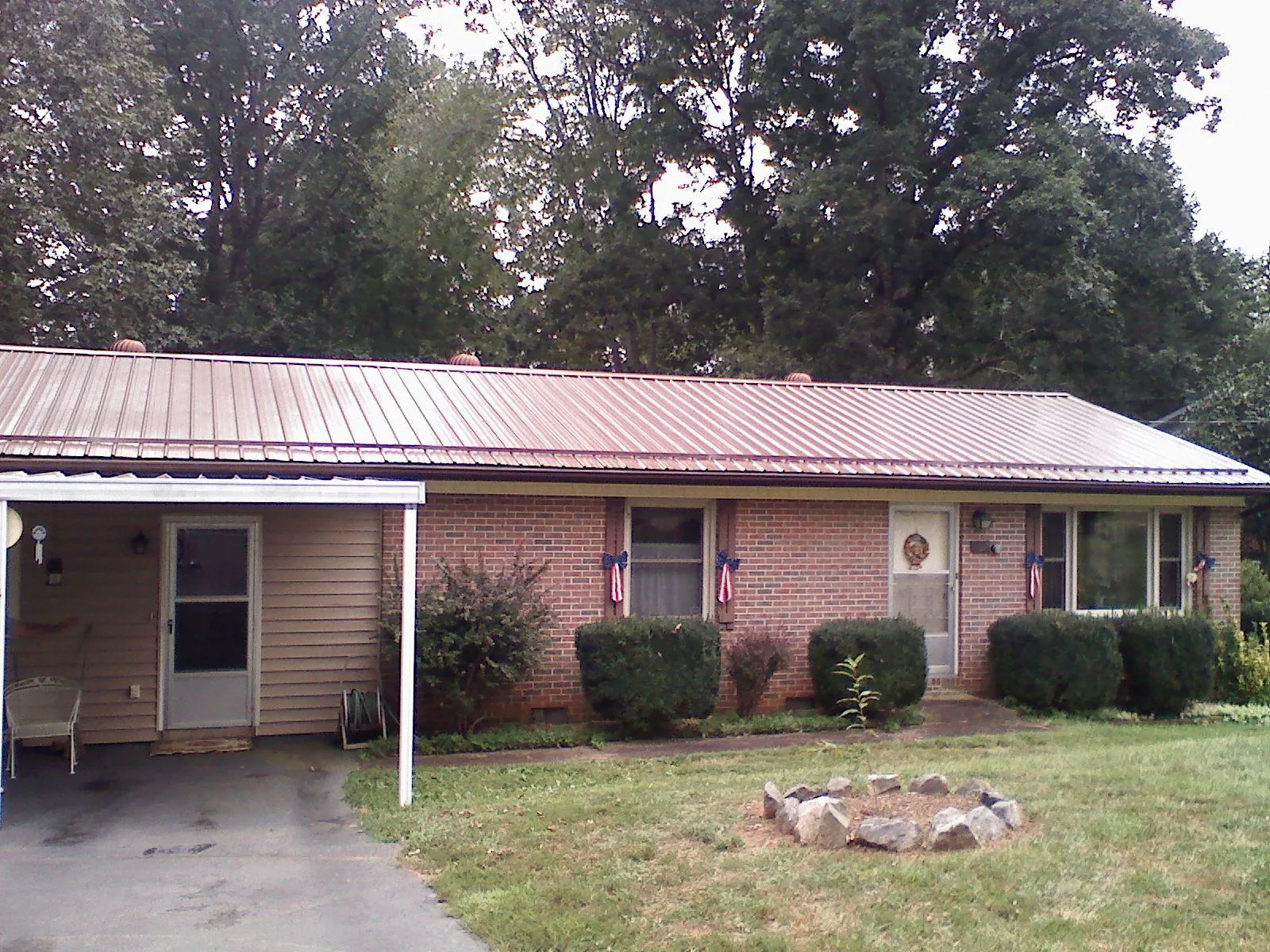 Bronze metal roof and carport on a brick ranch home — Roof Repair work by our crew in Carroll