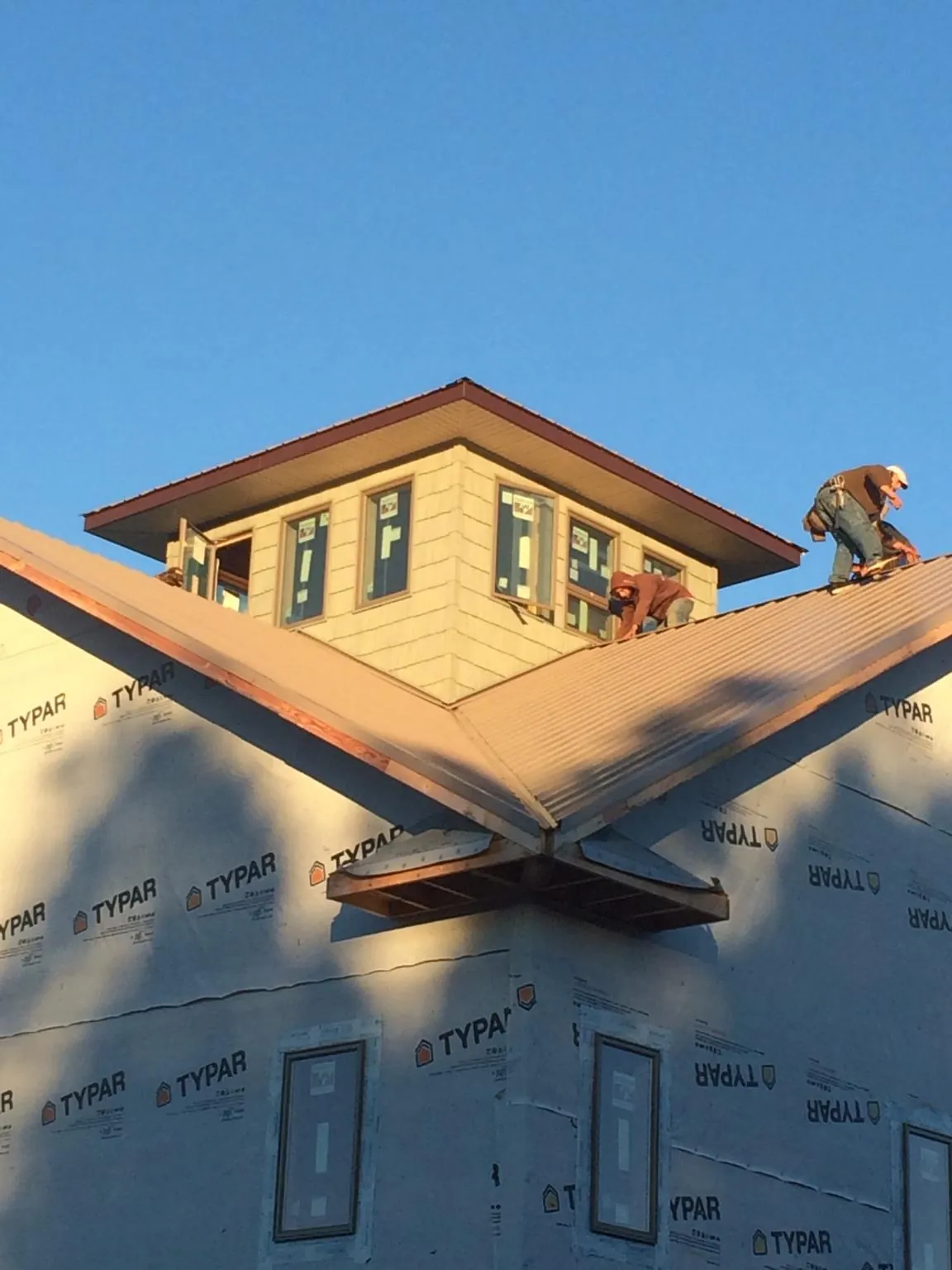 Roofers working around a rooftop cupola on a new metal roof at sunset — Roof Waterproofing in Carroll by Roofing Brothers